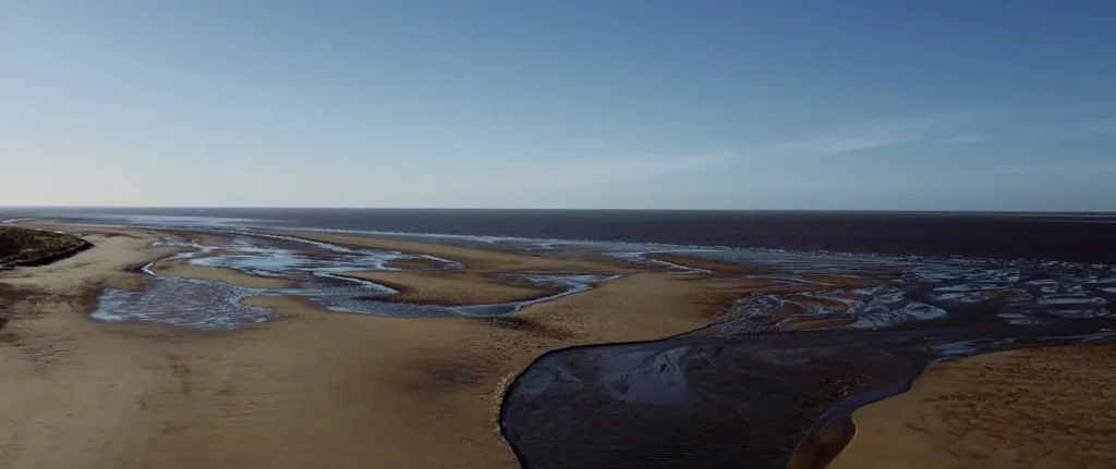 Still from the New Dawn drone video, showing an aerial view of a North Norfolk beach.