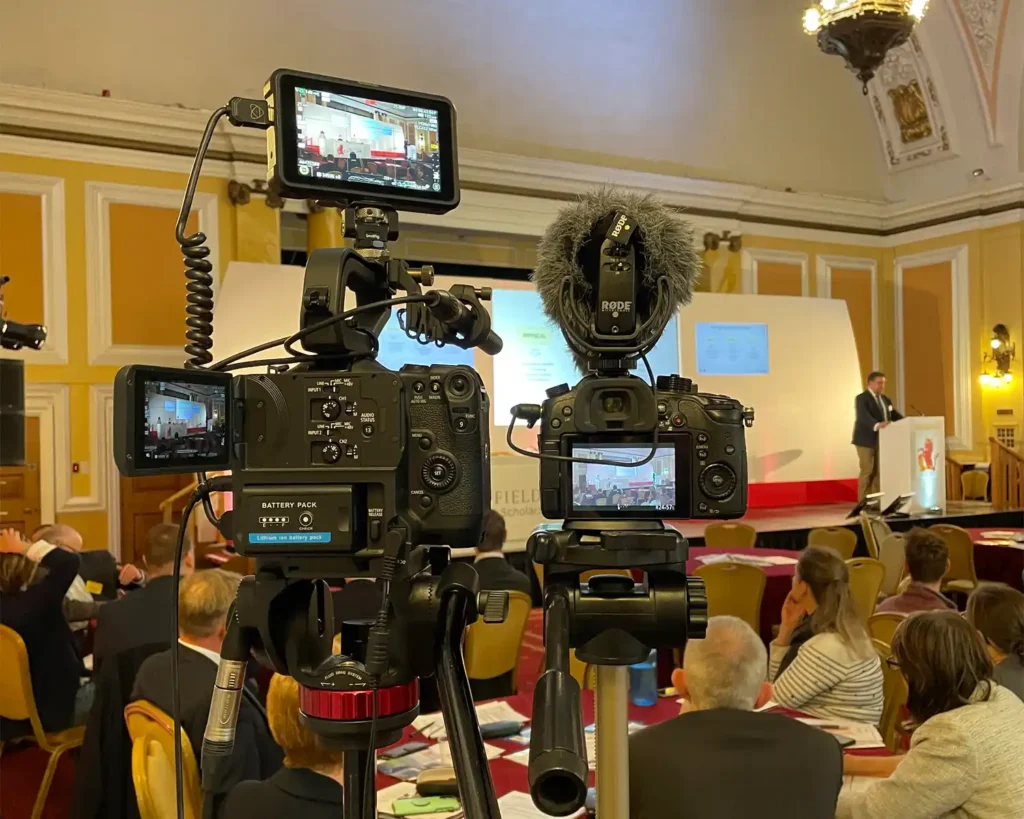 Photograph showing two high end cameras being used to film a corporate event.