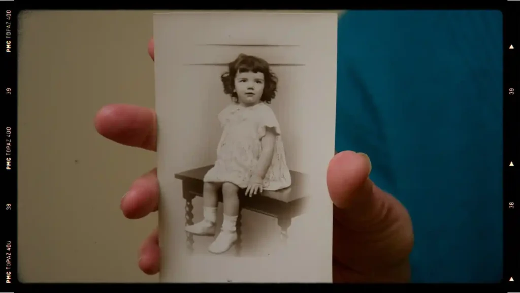 Still from the Something to Remember Me By documentary film, showing an older person holding a photo of themselves as a child.