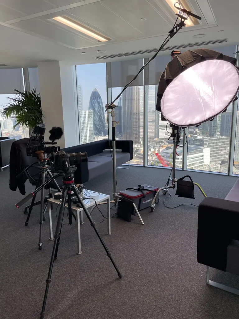 Behind the scenes of a video shoot in central London. The Gherkin can be seen out of the window and the foreground features high end video cameras, microphones and lighting