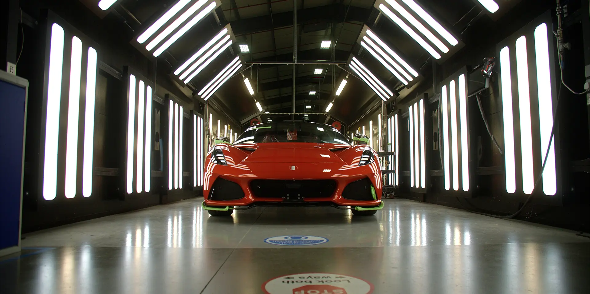 Still frame of the Lotus Cars events video showing a red Lotus car on the production line in the Lotus factory.