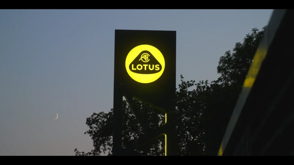Illuminated Lotus sign silhouetted against an evening sky and crescent moon.