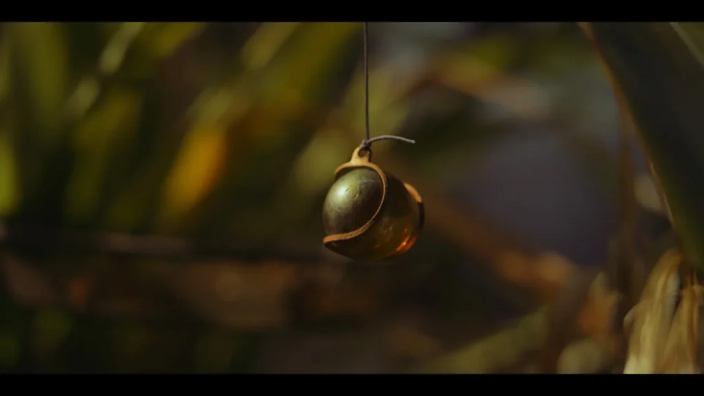 Glass and bronze ornament among softly blurred garden foliage.